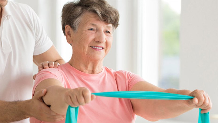 senior in rehabilitation exercising, using a stretch band